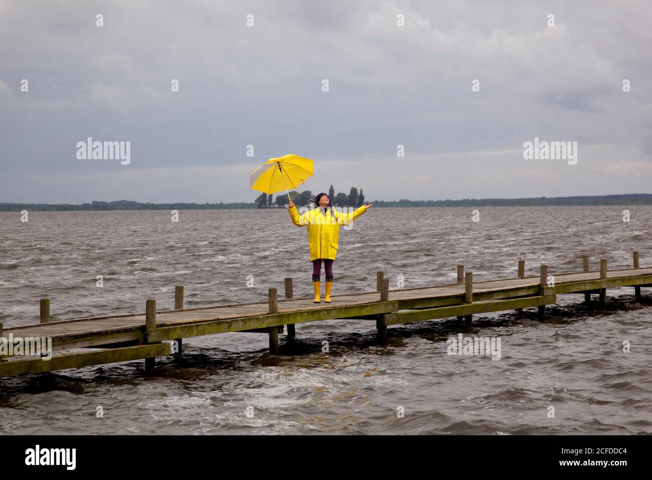Giovane donna sul jetty controlla 0b è ancora piovendo. Steinhuder Meer, Germania Foto Stock