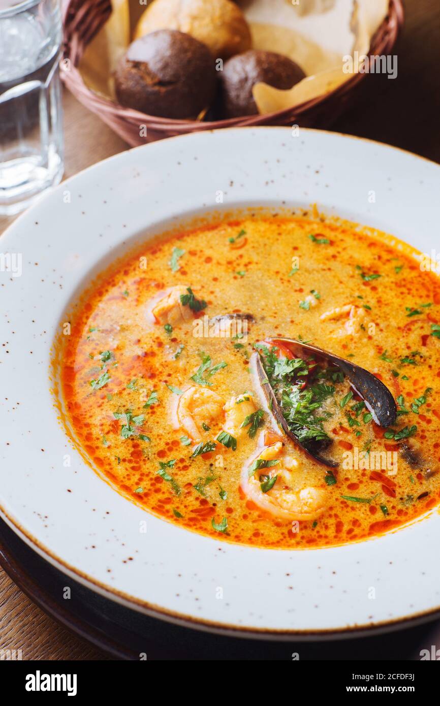 Dall'alto di appetitosa zuppa di pomodoro aromatica con funghi porcini ed erbe verdi servite su piatto bianco Foto Stock
