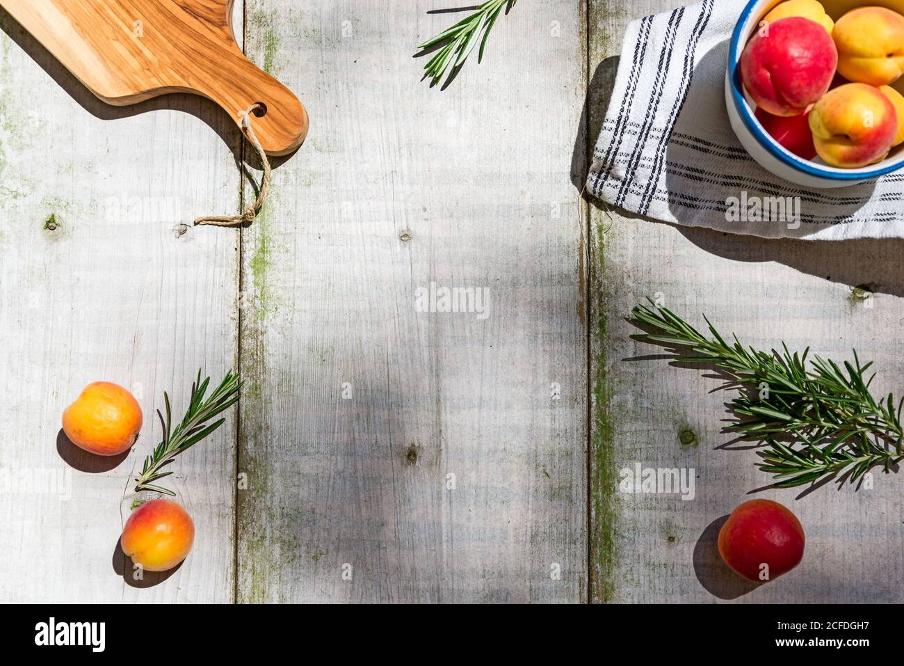 Tavolo da giardino decorato con albicocche e rosmarino, con spazio centrale per la copia Foto Stock