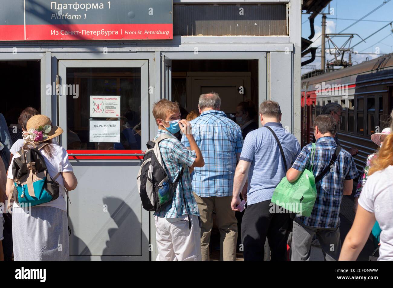 San Pietroburgo, Russia - 08 agosto 2020: I passeggeri in arrivo dal treno entrano nell'edificio della stazione a loro volta. Il giovane mascherato si guardò intorno. Foto Stock