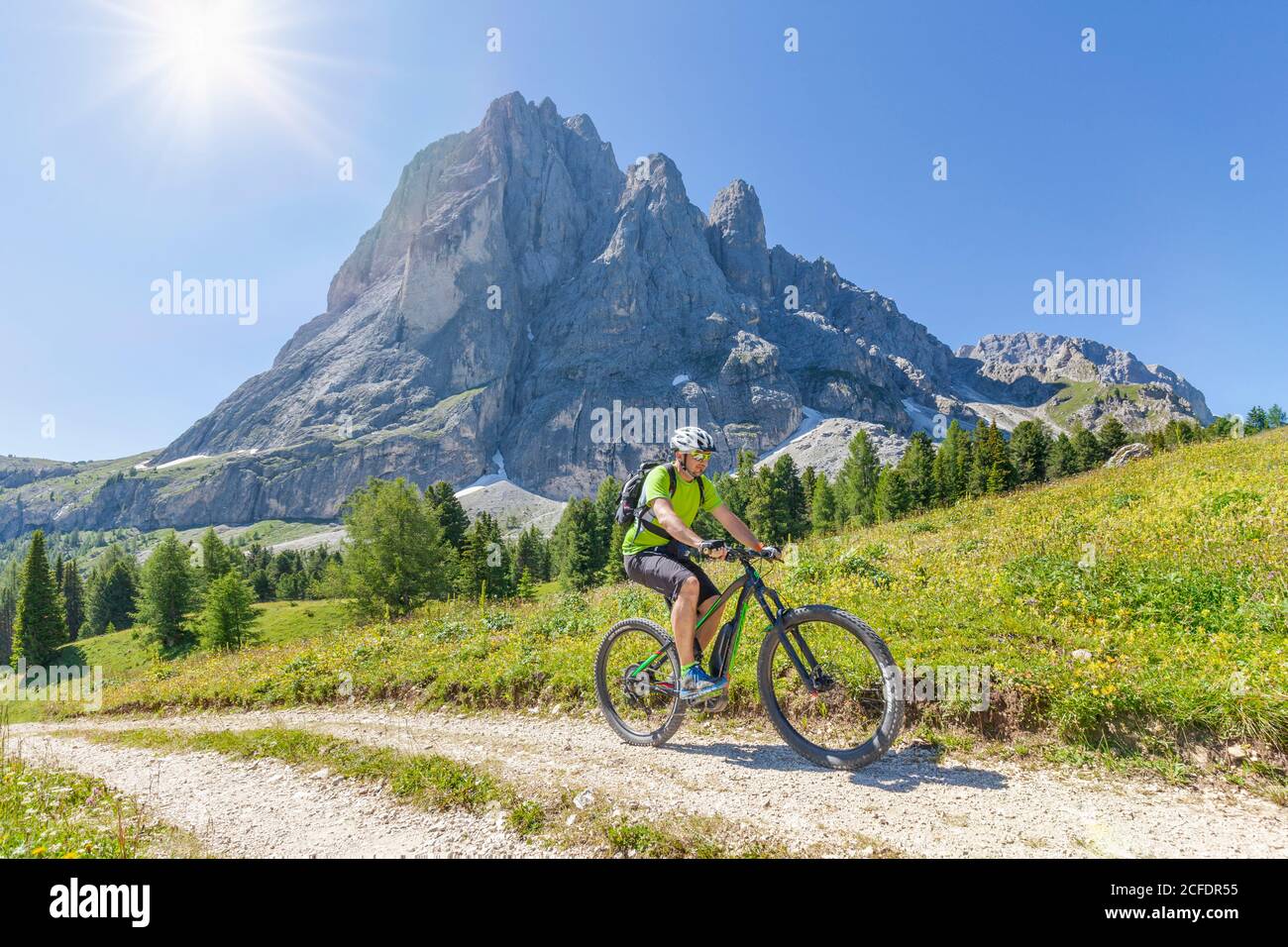 Ciclista con mountain bike (e-bike) pedalando ai piedi del Sassolungo Langkofel, Val Gardena, Grödental, Alto Adige, Dolomiti, Italia Foto Stock