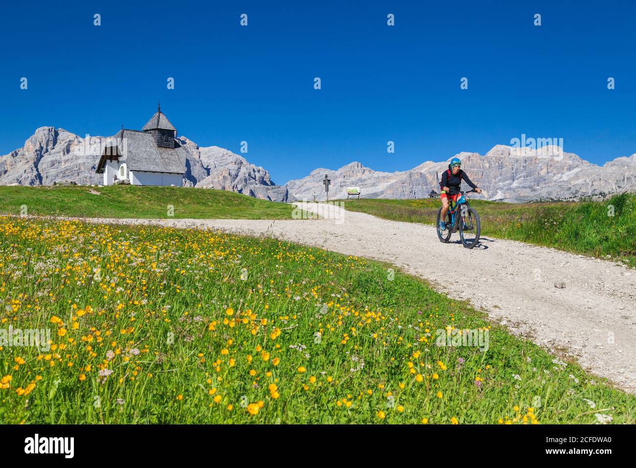Donna con e-bike sulla strada sterrata vicino alla cappella di Sant'Antonio, altopiano di Pralongia, Dolomiti, Corvara, alta Badia , Alto Adige, Italia, Foto Stock