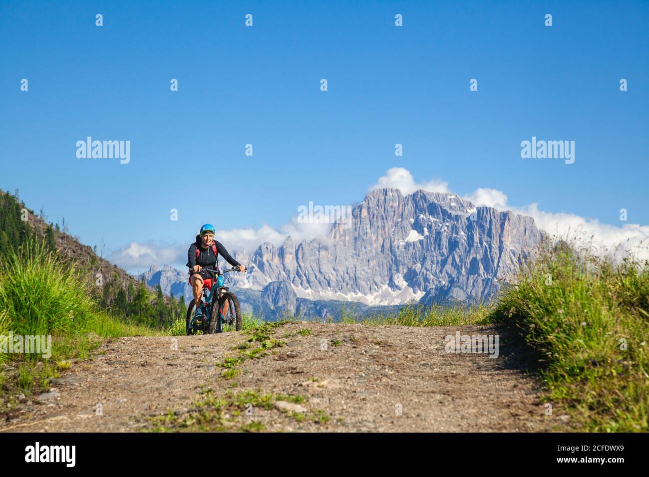 Donna pedalata su una strada sterrata, sullo sfondo il monte Civetta vicino al malmo di Cherz, tour con e-bike nel paesaggio naturale delle Dolomiti, Foto Stock