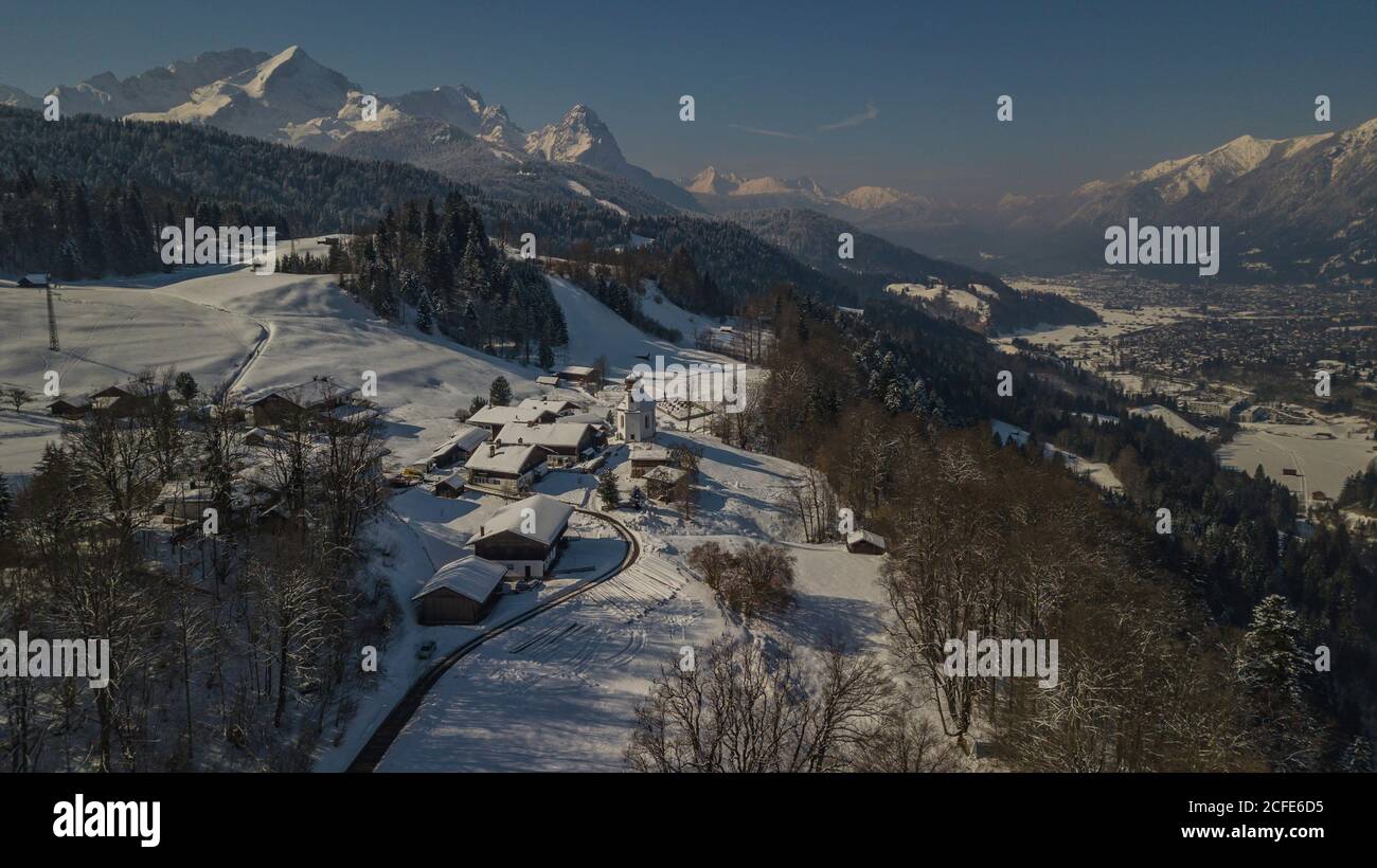 Vista aerea di Wamberg sopra Garmisch-Partenkirchen in inverno, cielo blu, Kirchdorf con Chiesa di Sant'Anna, vista in direzione Wetterstein Montagne con Foto Stock