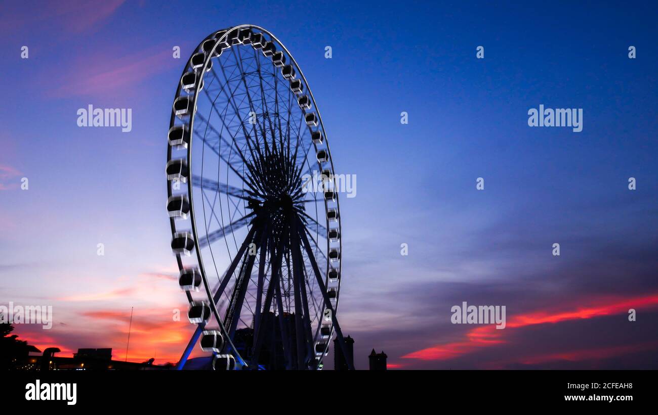 parte della ruota in ferro in movimento contro uno sfondo blu del cielo con luci dall'illuminazione notturna dopo il tramonto. sfondo della ruota in ferro per la carta da parati Foto Stock