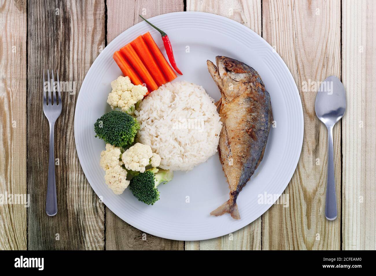 Sgombro fritto con salsa di peperoncino cibo stile tailandese. Cibo sano. Sgombro con carote e broccoli su piatto bianco su tavolo di legno dall'alto vi Foto Stock