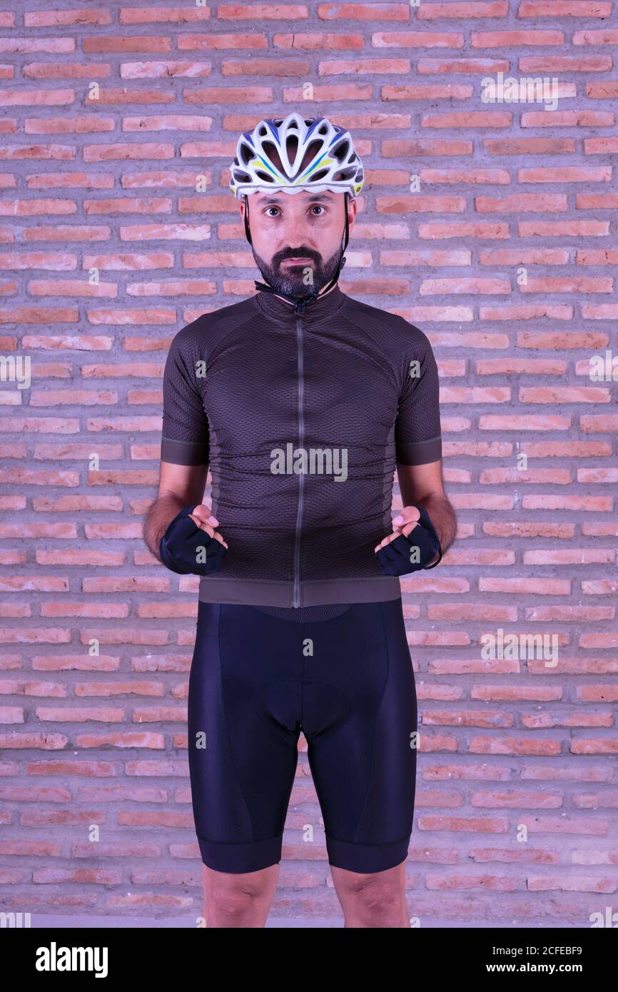 Sicuro giovane ciclista maschile in abbigliamento sportivo guardando la fotocamera con determinazione Foto Stock