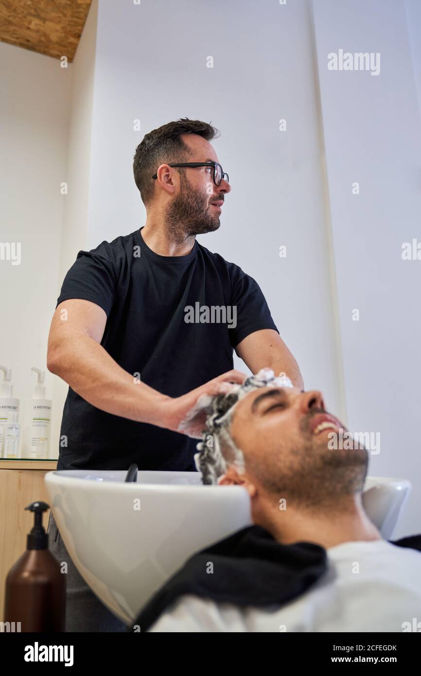 Stock verticale foto di un barbiere lavando la testa di un cliente con  shampoo e guardando intorno. Barbiere Foto stock - Alamy