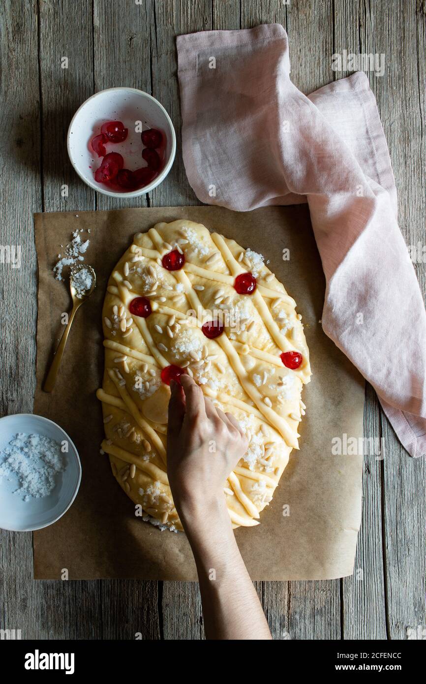 Da sopra persona irriconoscibile decorazione tradizionale Coca de San Juan pasticceria mentre cucinando su tavola di legno in cucina Foto Stock