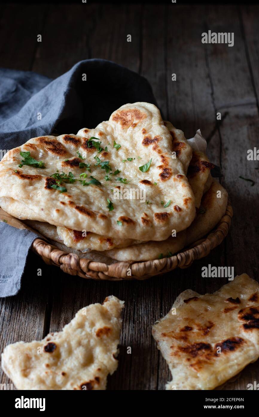 Piatto con delizioso pane naan e tovagliolo di stoffa messo sopra tavolo di legno intemperie Foto Stock