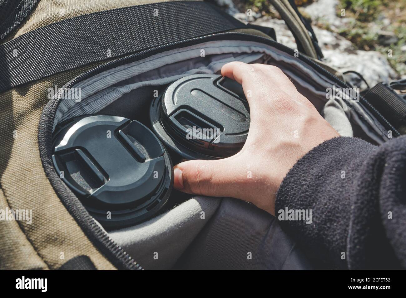 mani irriconoscibili di una persona che afferra un obiettivo da un zaino per fotografi professionisti aperto Foto Stock