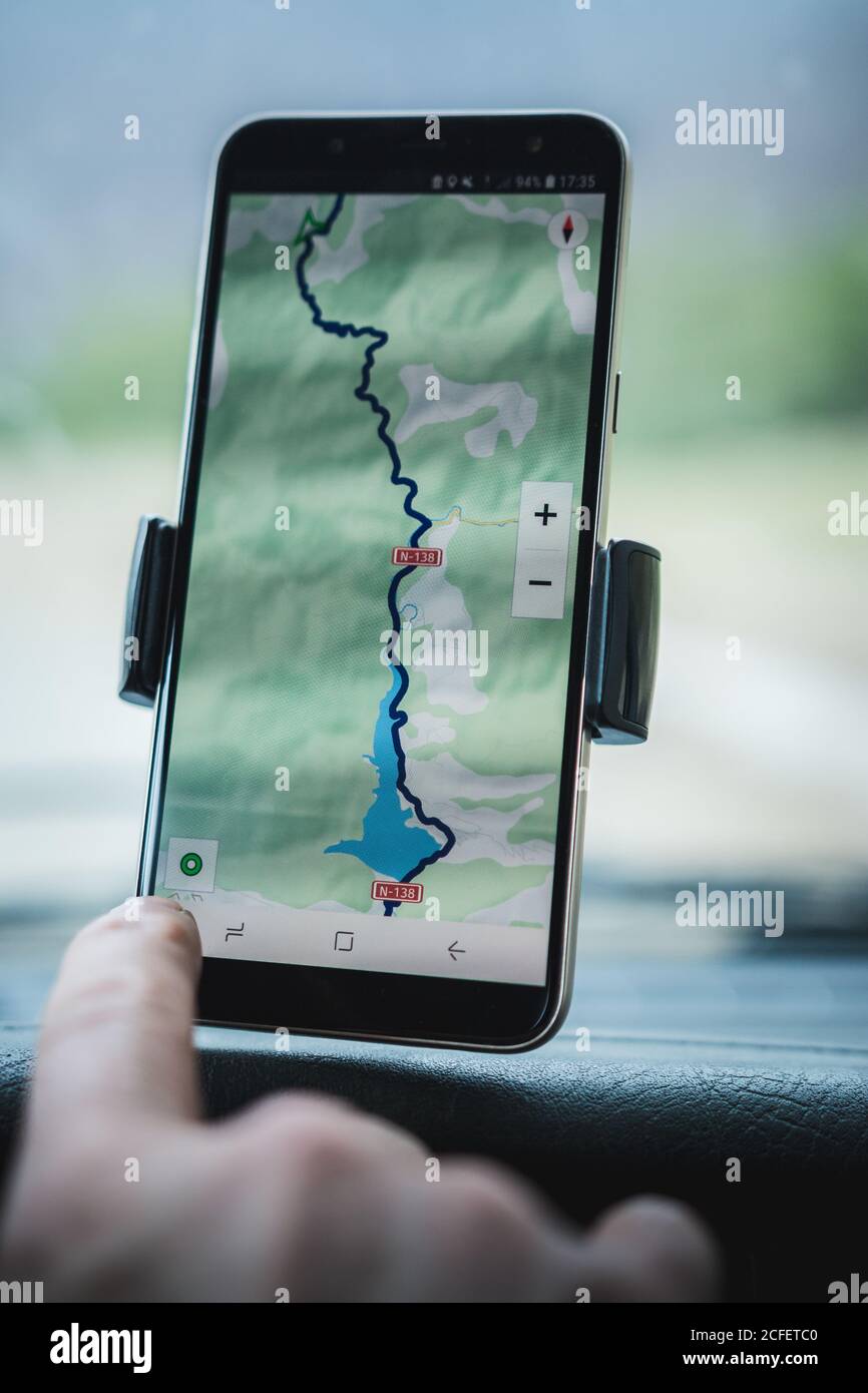 Closeup mano di turista anonimo utilizzando navigatore GPS su moderno smartphone in auto durante il viaggio Foto Stock