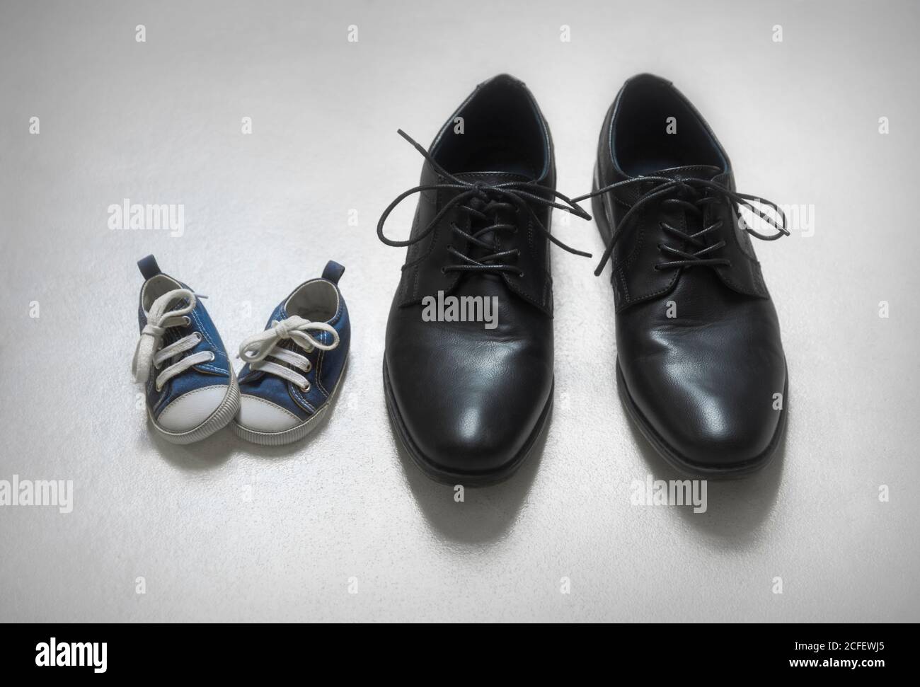 Padre con la metafora del figlio, scarpe per bambini e adulti. Foto Stock