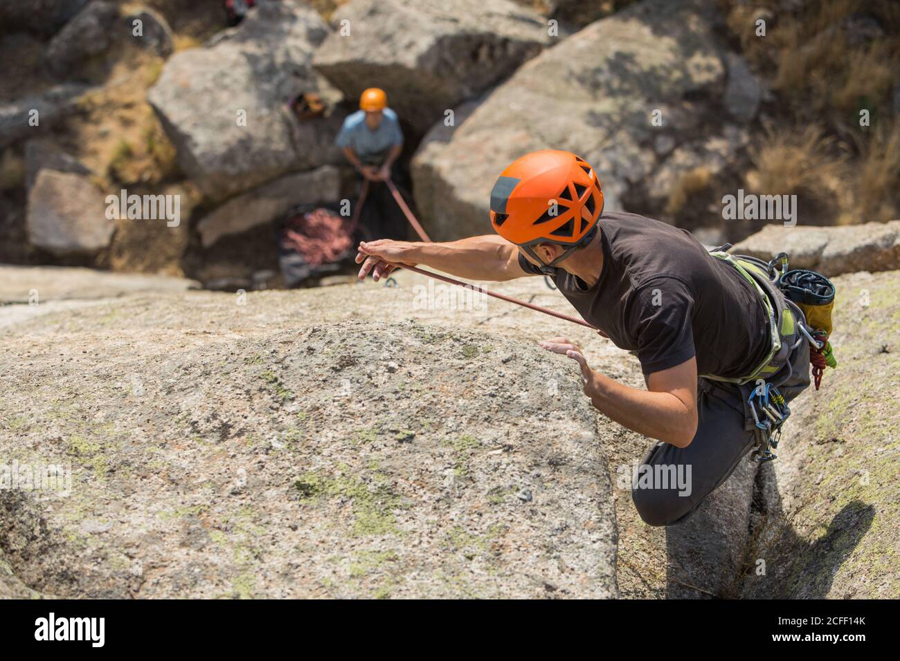 Dall'alto giovani avventurieri che arrampicano in montagna indossando imbracatura di sicurezza contro paesaggio pittoresco Foto Stock