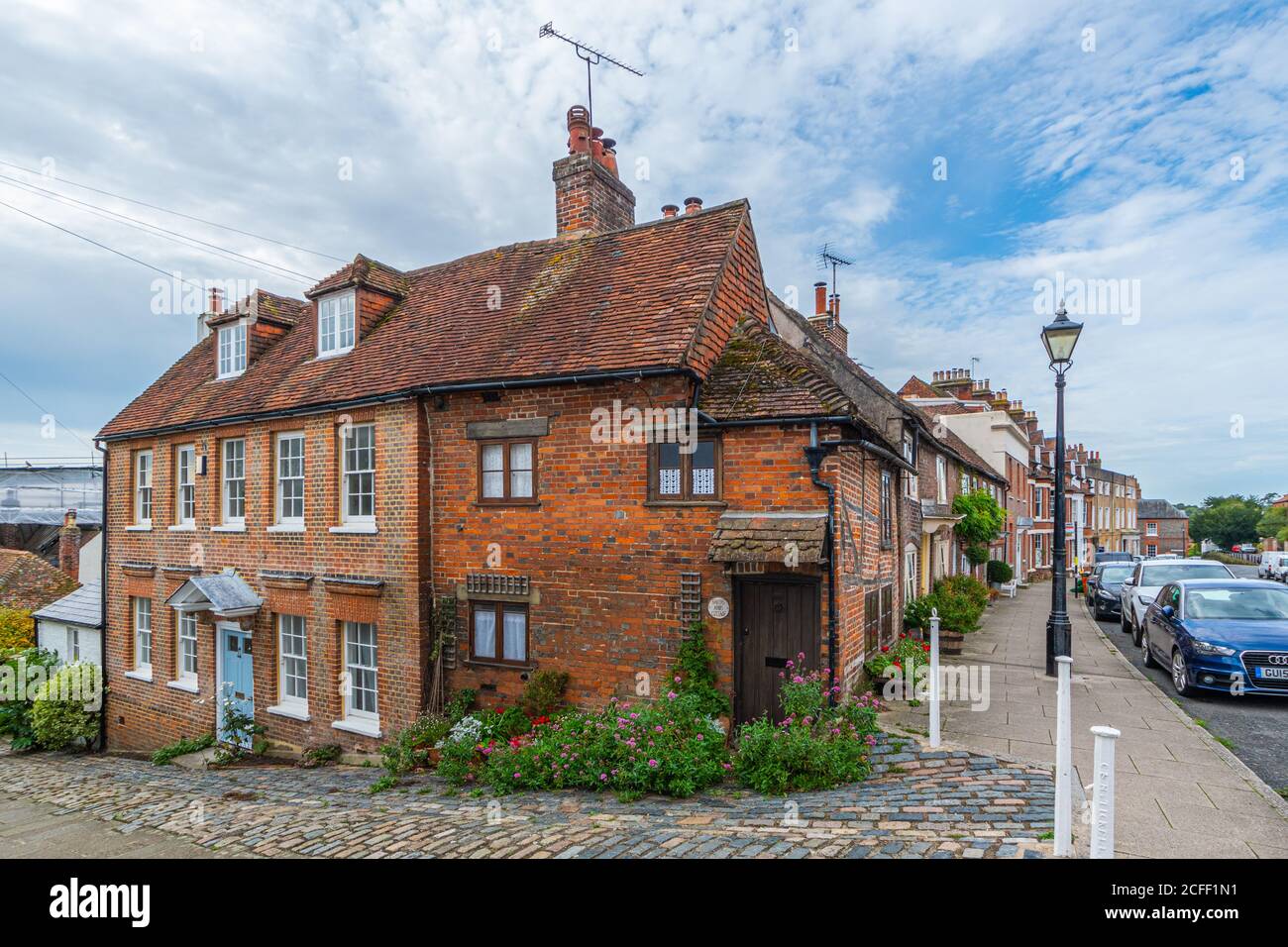 Bakers Arms Cottage, vecchio piccolo cottage in mattoni rossi incorniciato vicino a nuove case georgiane all'angolo di Bakers Arms Hill, Arundel, West Sussex, UK. Foto Stock