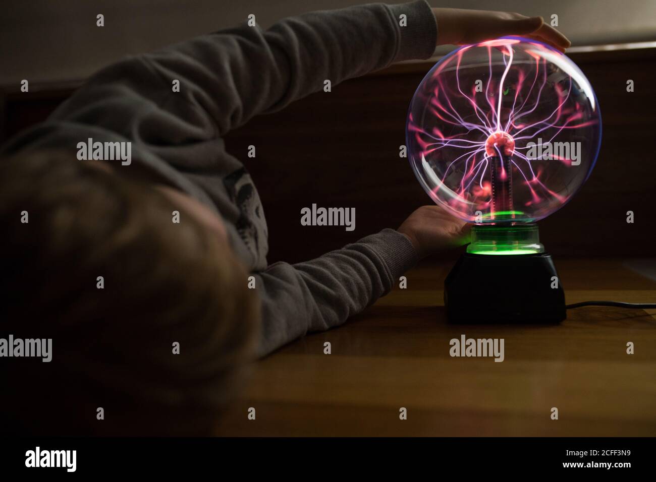 ragazzo che guarda la misteriosa lampada in vetro che illumina il tavolo Foto Stock