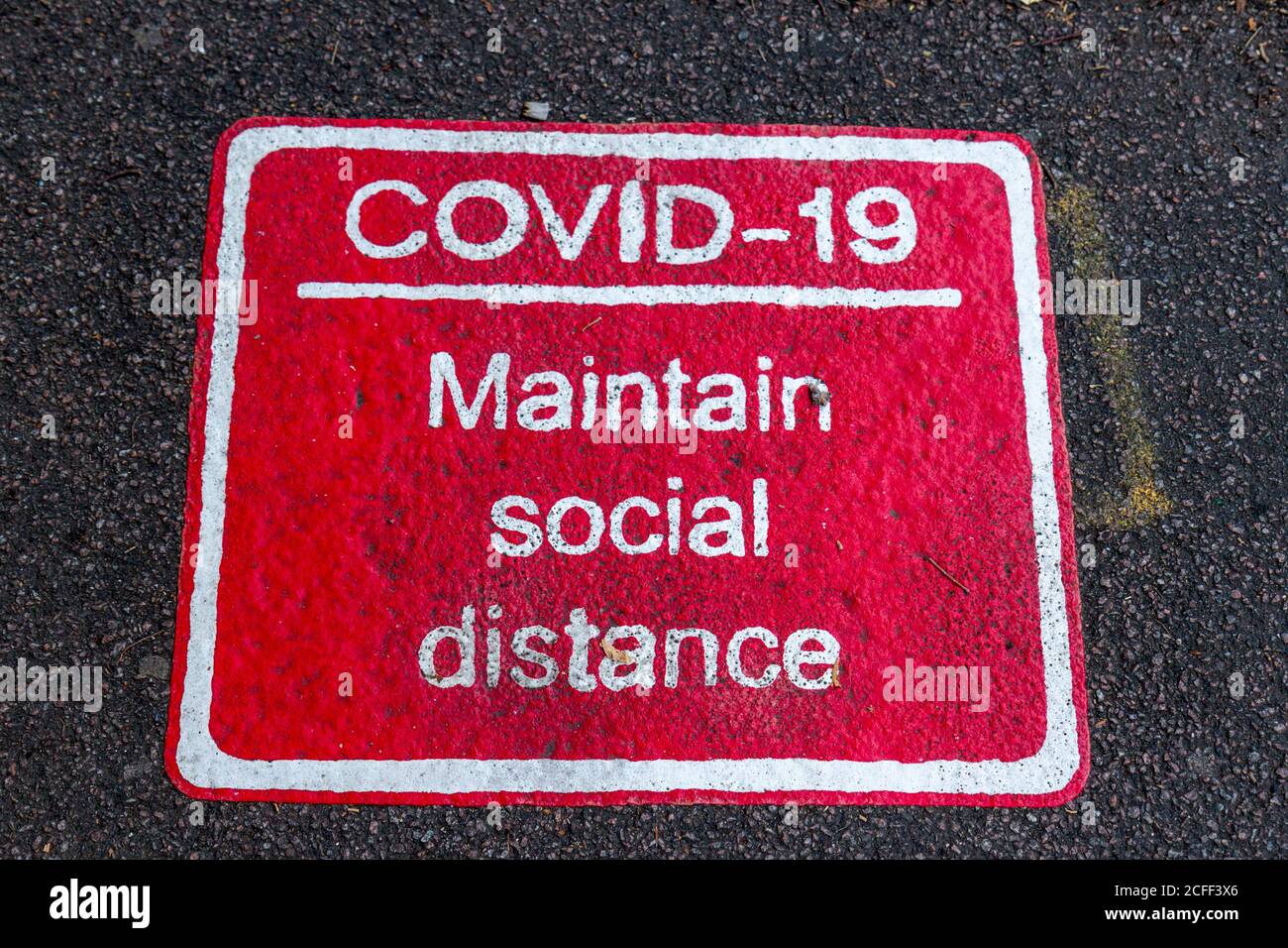 Il cartello "COVID-19 maintain social distance" (mantenere la distanza sociale) è stato dipinto in un marciapiede durante la pandemia del Covid-19 del 2020 a Cambridge, Regno Unito. Foto Stock