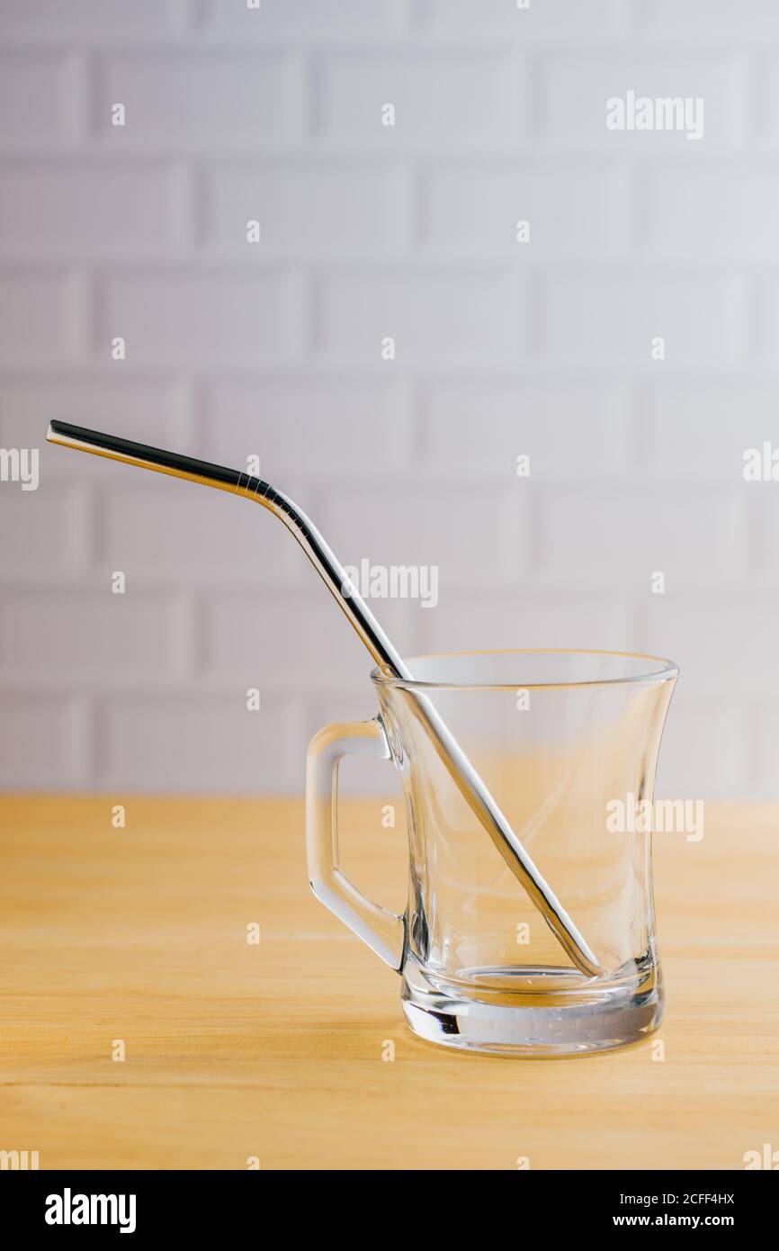 Acciaio lucido eco-compatibile paglia sostenibile in vetro vuoto su tavolo di legno Foto Stock