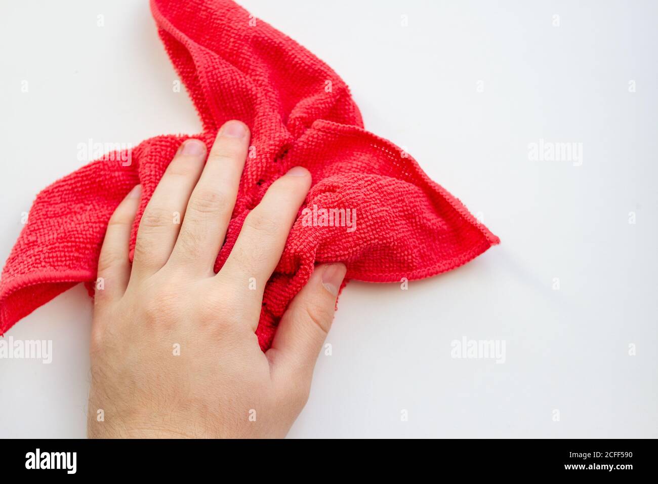mano con panno in microfibra rossa su sfondo bianco. Pulizia della casa Foto Stock