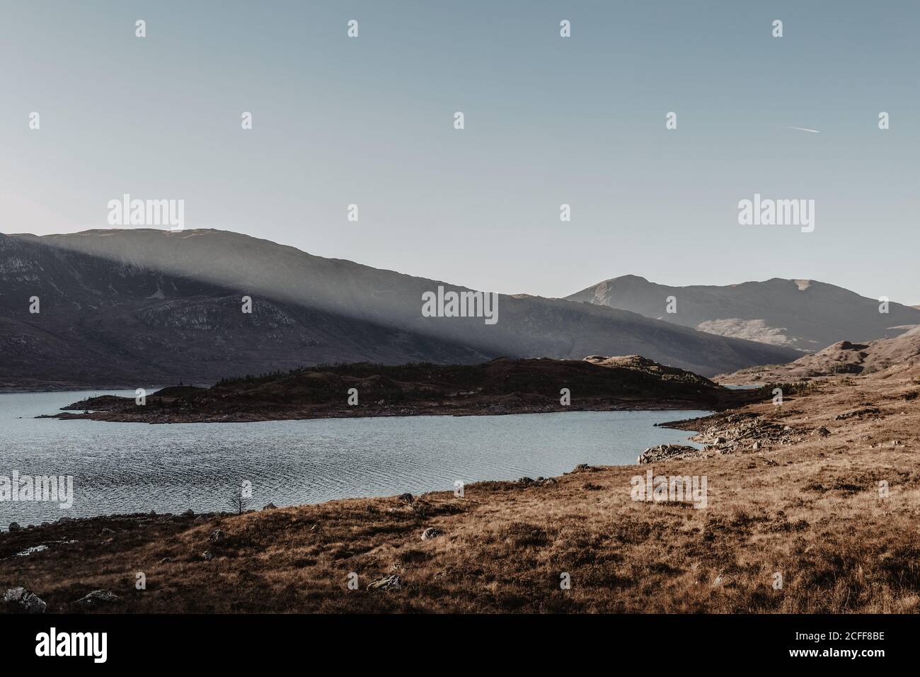 Paesaggio panoramico di montagna con rocce e lago contro chiaro cielo blu all'alba Foto Stock