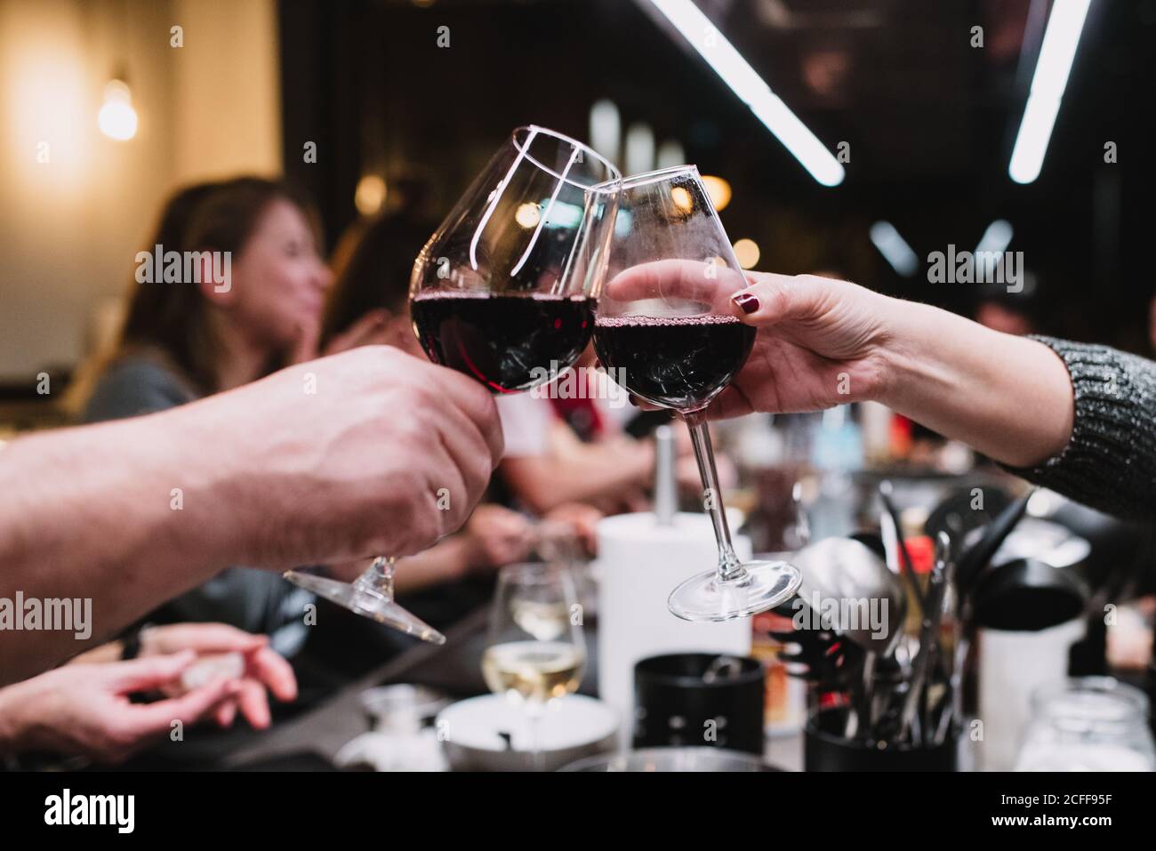 Persone irriconoscibili che si aggraffano gli occhiali da vino e che propongono toast mentre si cena in laboratorio di cucina dopo lezione a Navarre, Spagna Foto Stock