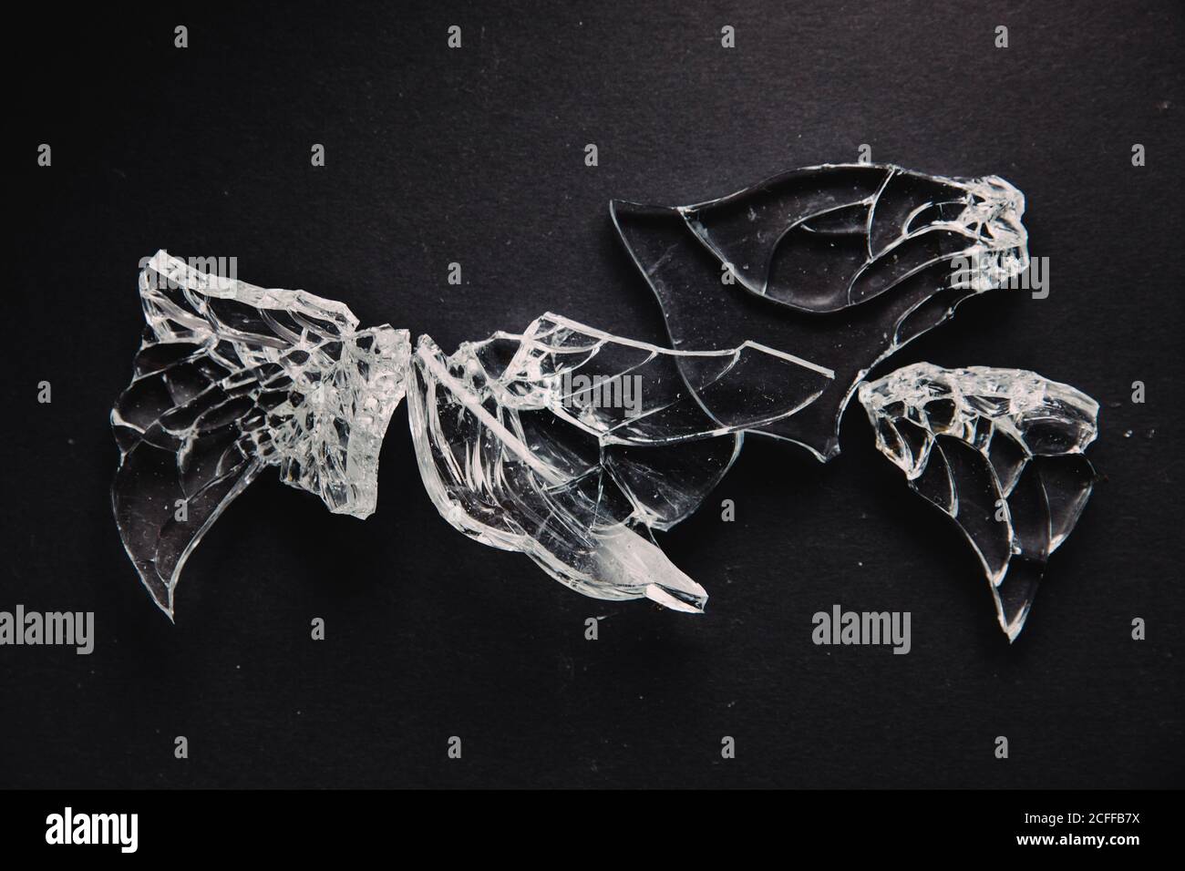 Sfondo astratto con pezzi lucidi di vetro trasparente rotto su superficie scura come concetto di falsi cristalli e gemme Foto Stock