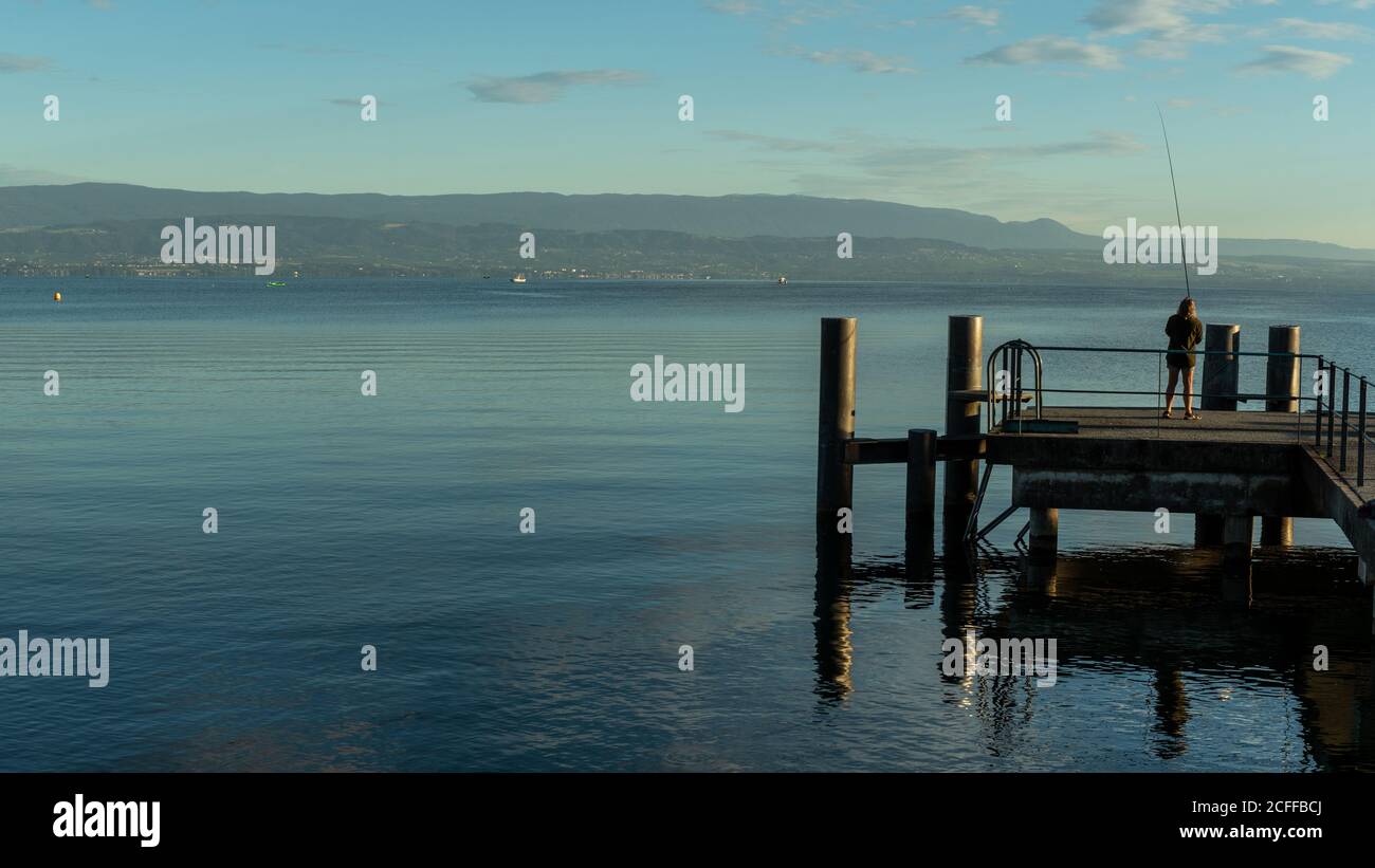 Un pescatore su un molo vicino al lago di Ginevra, Francia Foto Stock