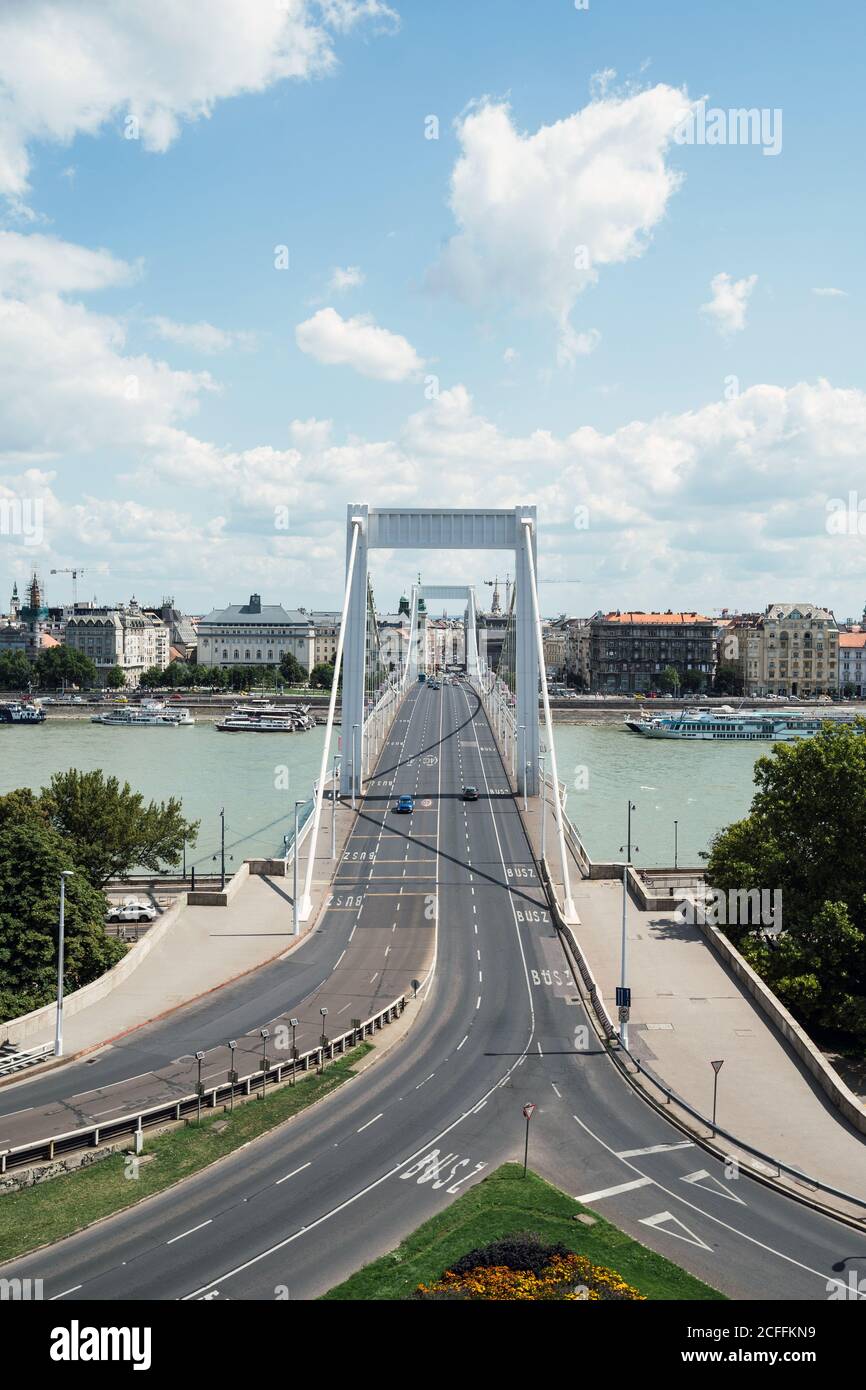 Da sopra strade asfaltate grigie che si collegano con il grande ponte Costruzione sopra il fiume calmo in un giorno nuvoloso a Budapest Foto Stock