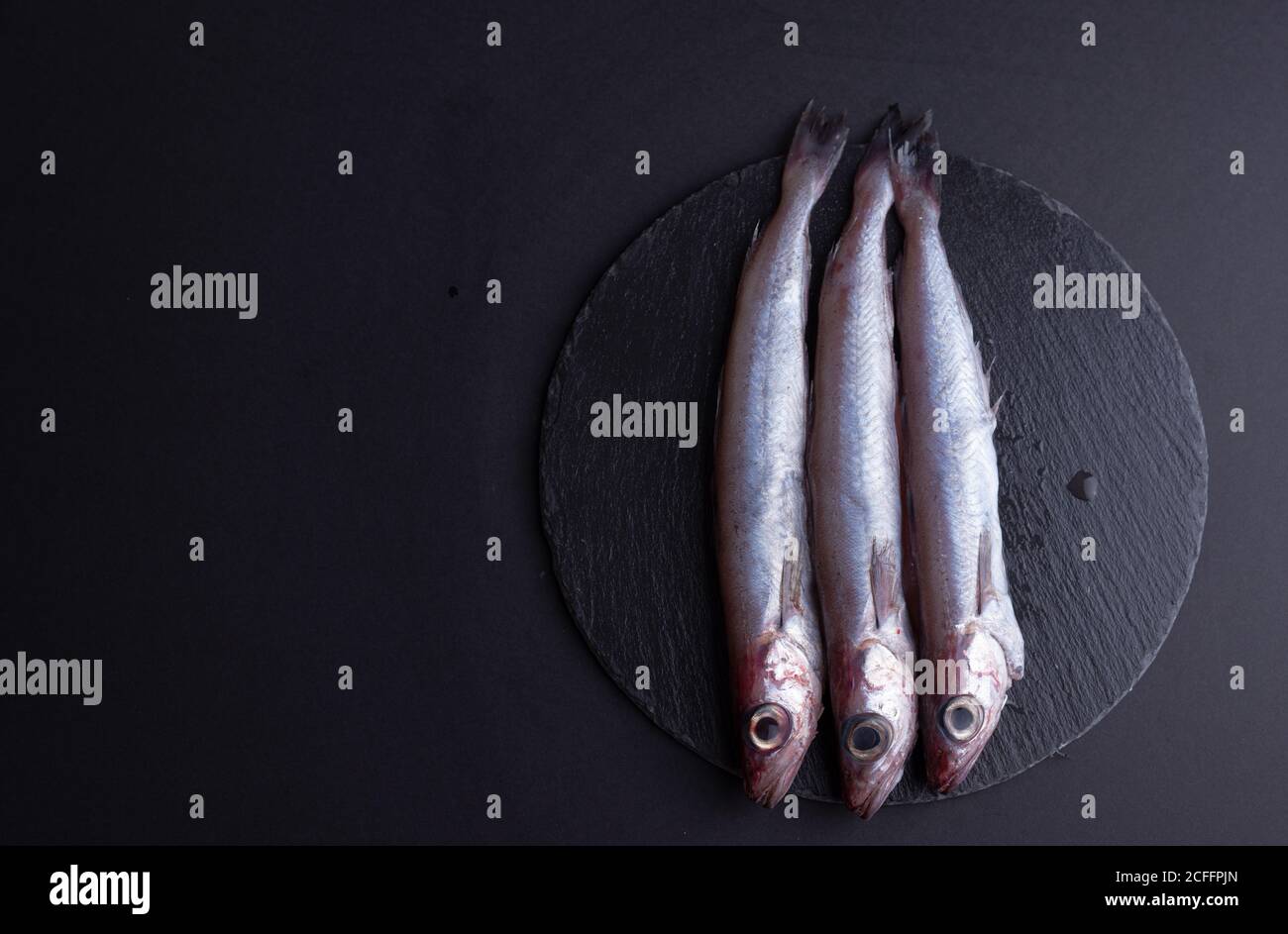Vista dall'alto del pesce crudo odorato posto su un tavolo nero in cucina Foto Stock