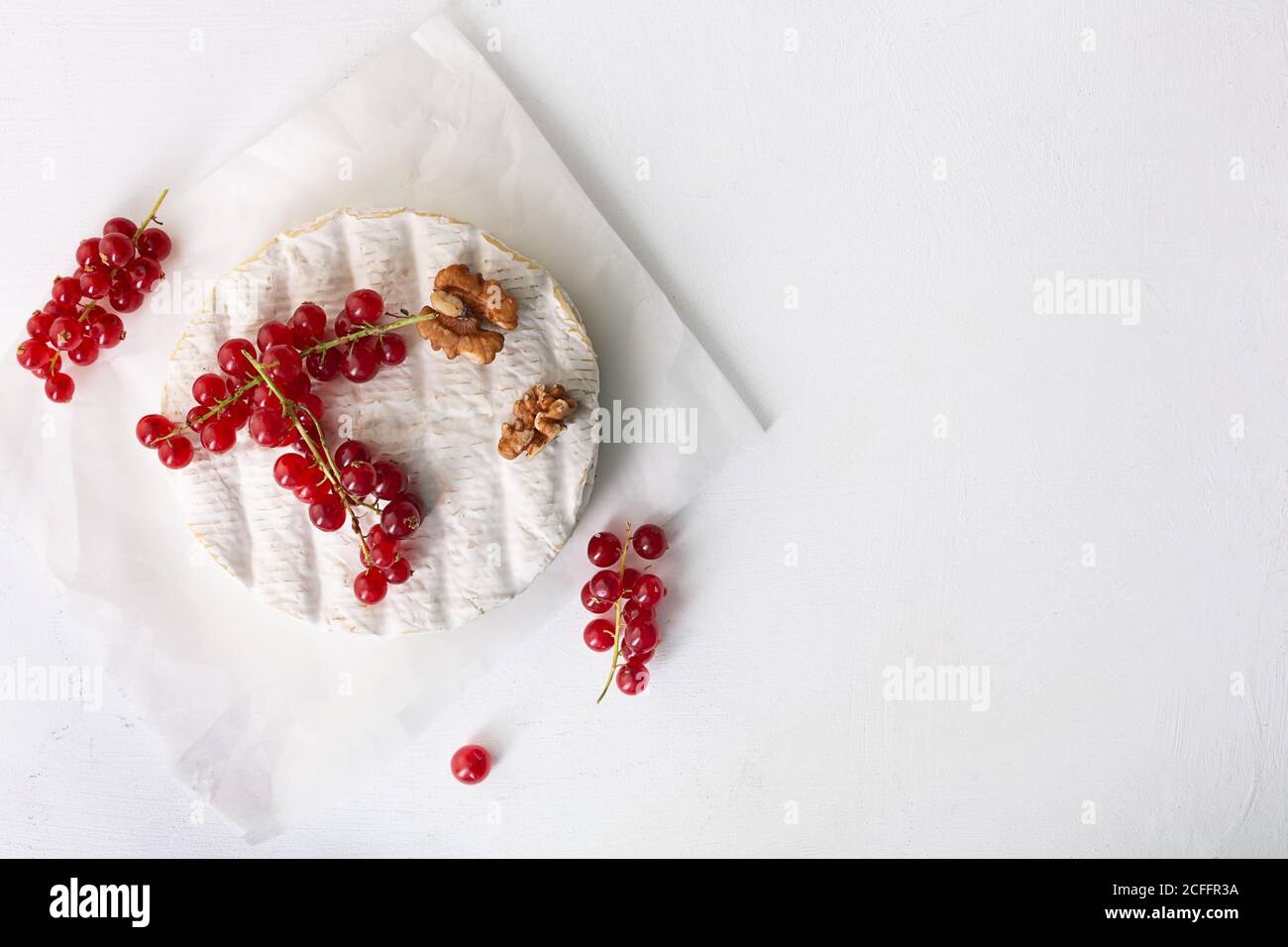 Formaggio Camembert con frutta, noci e bacche su sfondo bianco con spazio copia, vista dall'alto Foto Stock
