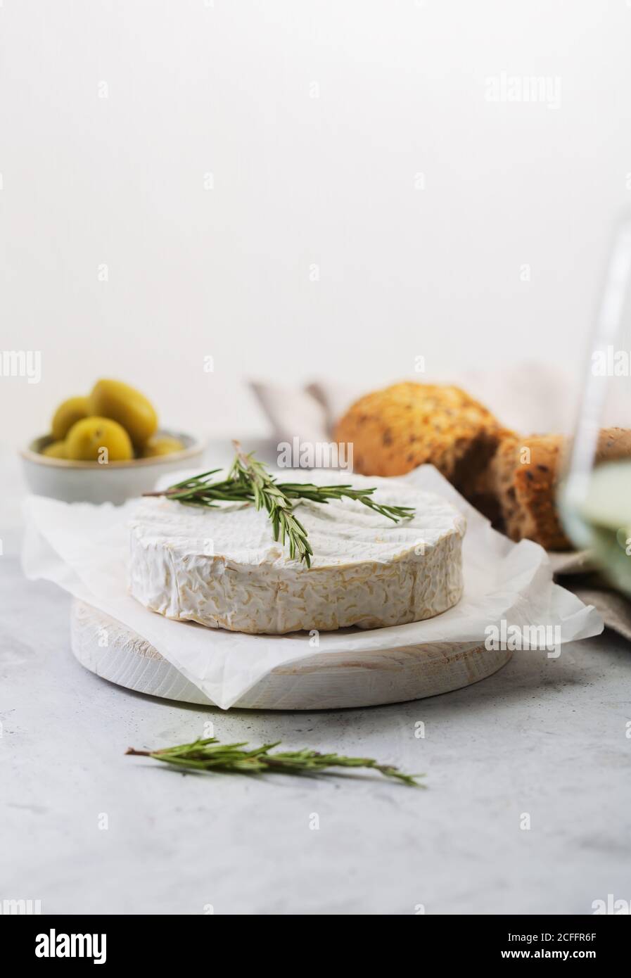 Formaggio Camembert con rosmarino e olive su fondo bianco con spazio per la copia Foto Stock