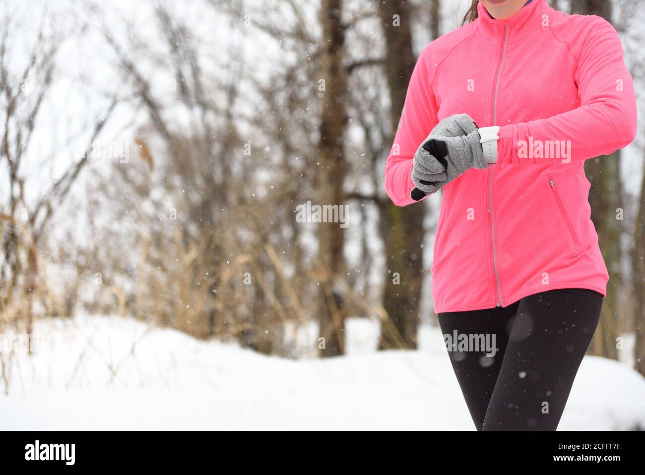 Runner che usa lo smartwatch per correre in inverno Foto Stock