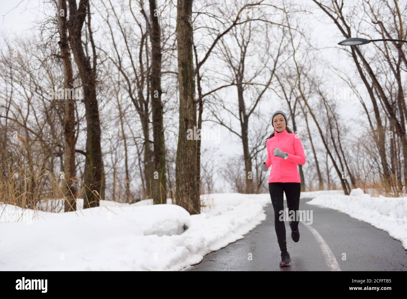 Donna che corre nel parco cittadino innevato - fitness invernale Foto Stock