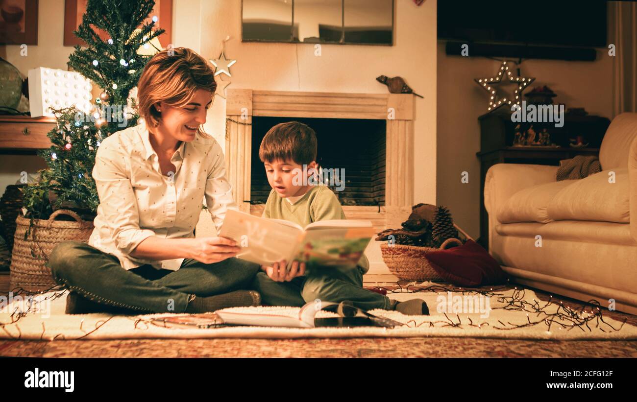 Libro di lettura della madre con il figlio alla vigilia di Natale Foto Stock