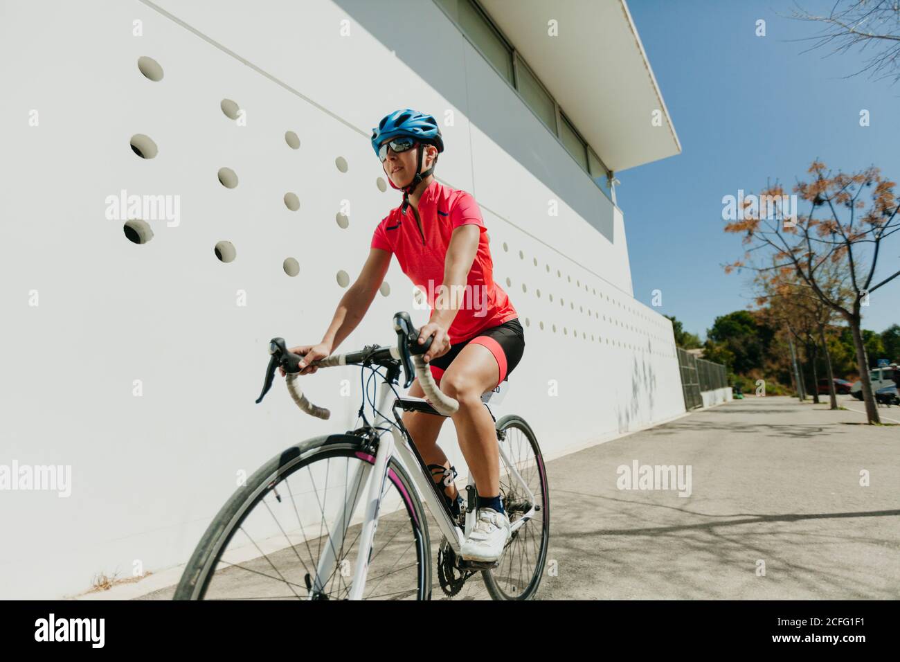 Donna in casco e bici da equitazione sportiva su strada il giorno di sole Foto Stock