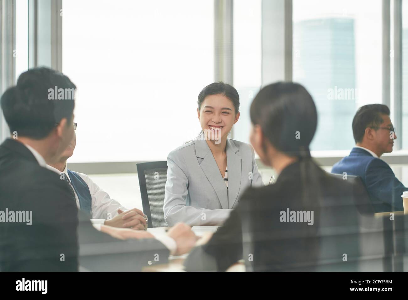 giovane donna asiatica d'affari che ride durante la riunione di squadra in ufficio Foto Stock