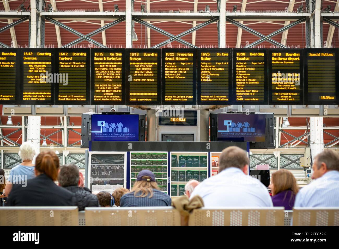 Passeggeri non riconosciuti che controllano l'orario del treno alla stazione ferroviaria di Paddington Foto Stock