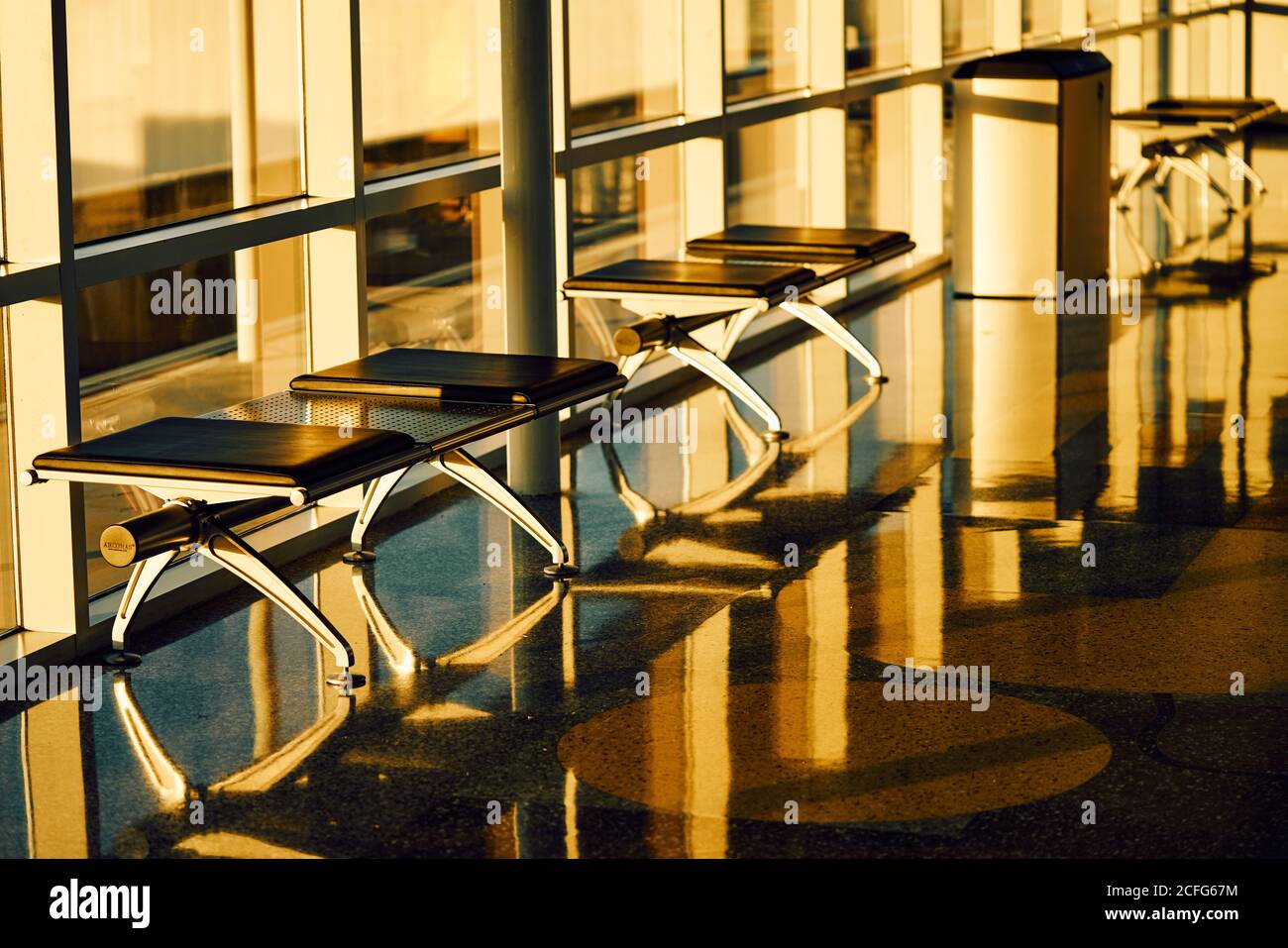 Panca in metallo con sedili in pelle nera lungo parete in vetro Soleggiato corridoio dell'aeroporto in Texas Foto Stock