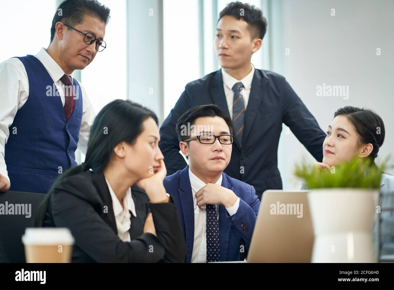 team di dirigenti aziendali asiatici che si riunono per discutere l'uso aziendale computer portatile Foto Stock