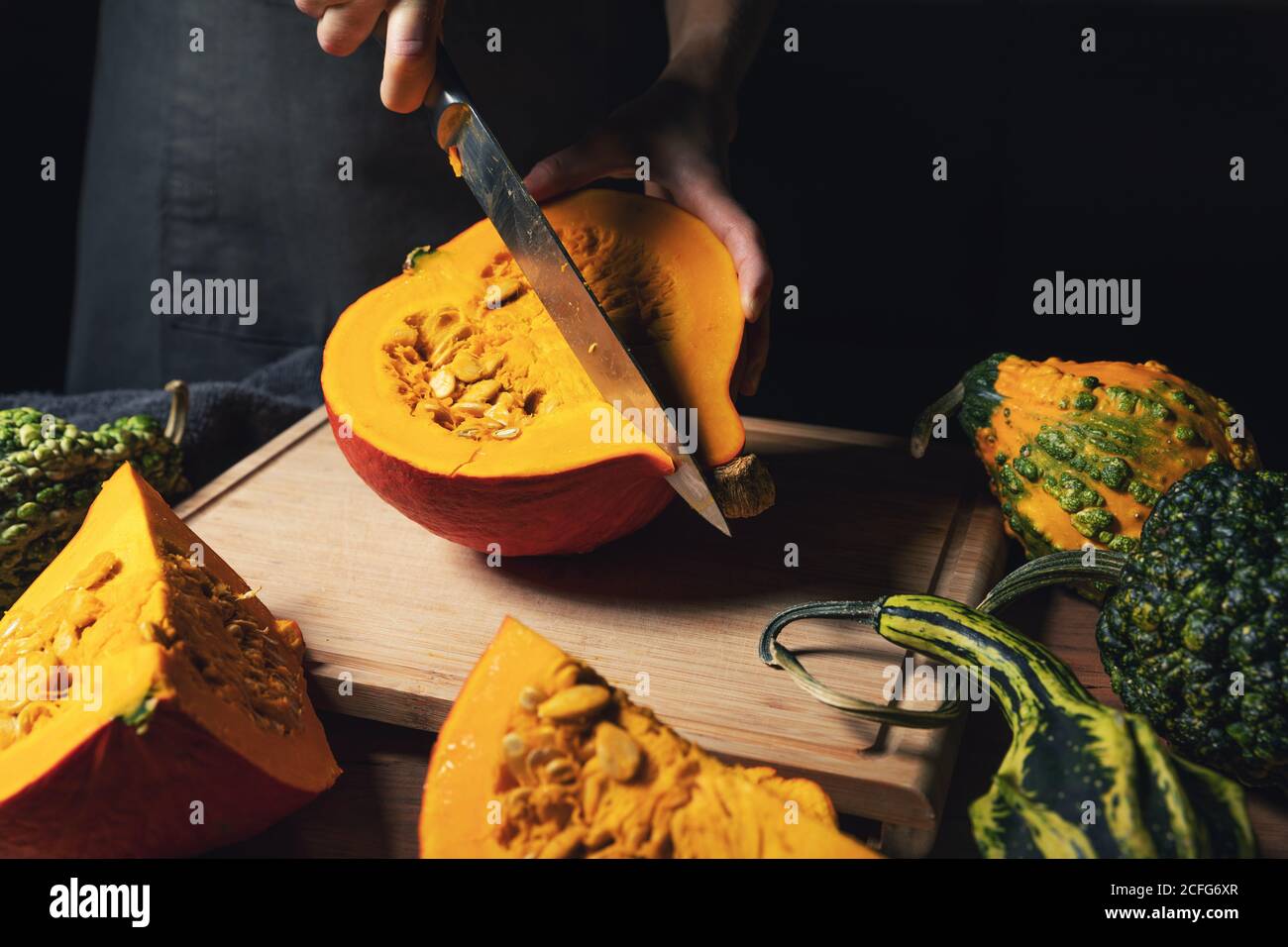 autunno stagione raccolto - donna taglio zucca con coltello per cucina su tavola di legno Foto Stock