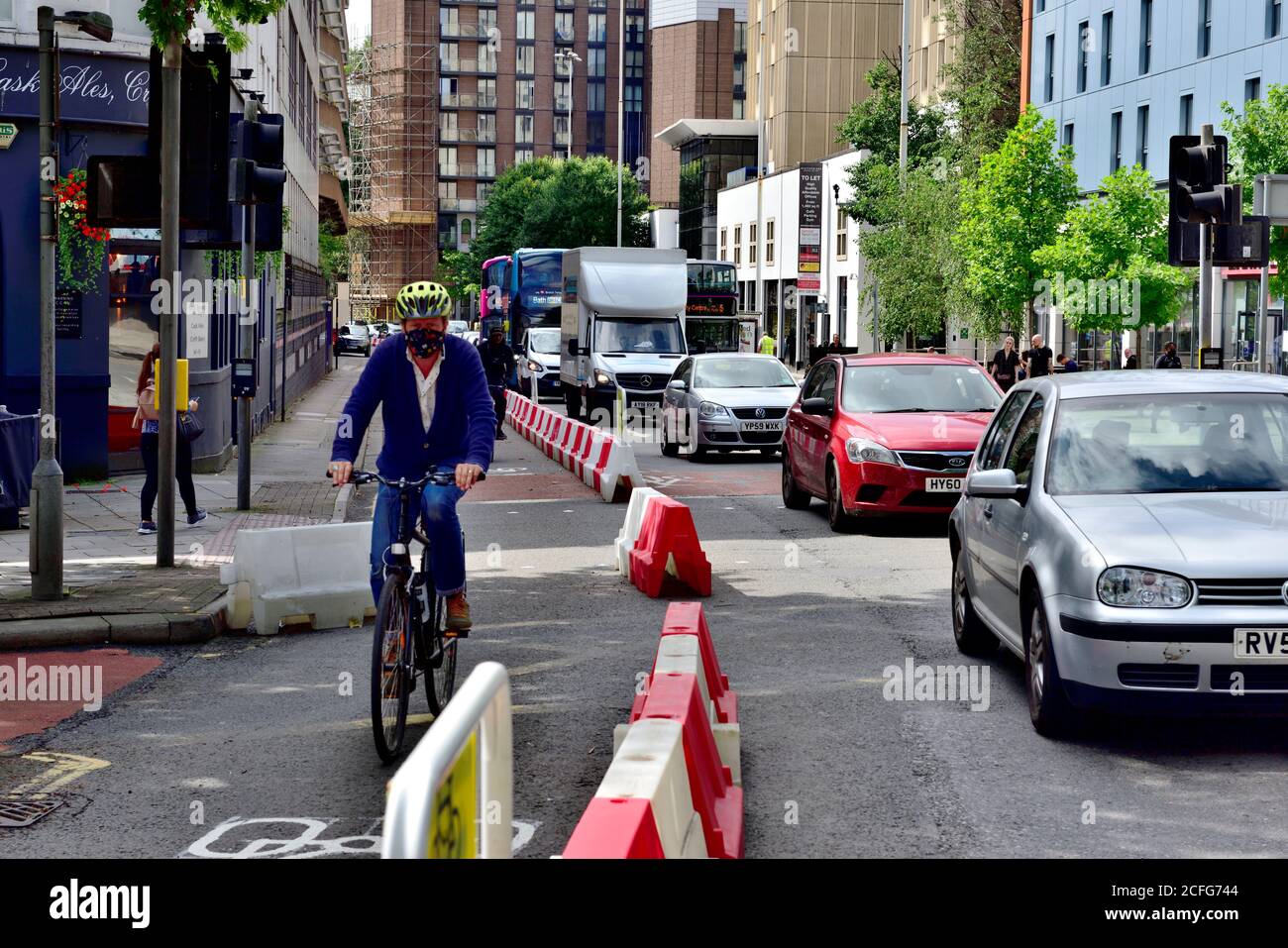 Ciclista singola in una nuova corsia di ciclo segregata su strada con lunga coda di traffico in una sola corsia di veicolo, Bristol, Regno Unito Foto Stock