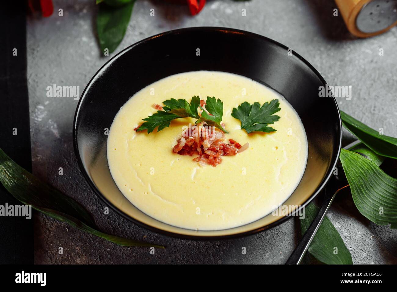 ciotola di gustosa zuppa di crema di formaggio con pancetta su un sfondo grigio Foto Stock