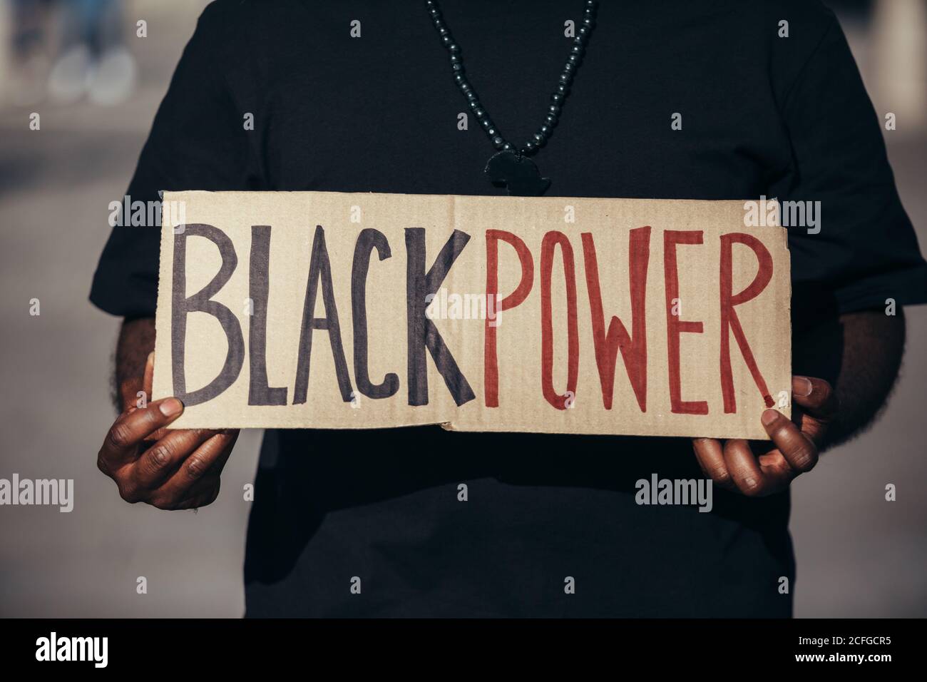 L'uomo anonimo protestando ad un rally per l'uguaglianza razziale che tiene un manifesto del 'potere nero'. Le vite nere contano. Foto Stock