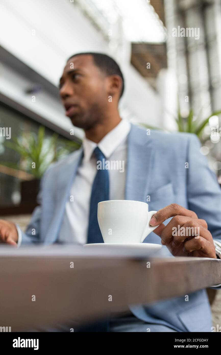 Uomo d'affari nero seduto alla scrivania con una tazza di caffè appena fatto caffè Foto Stock