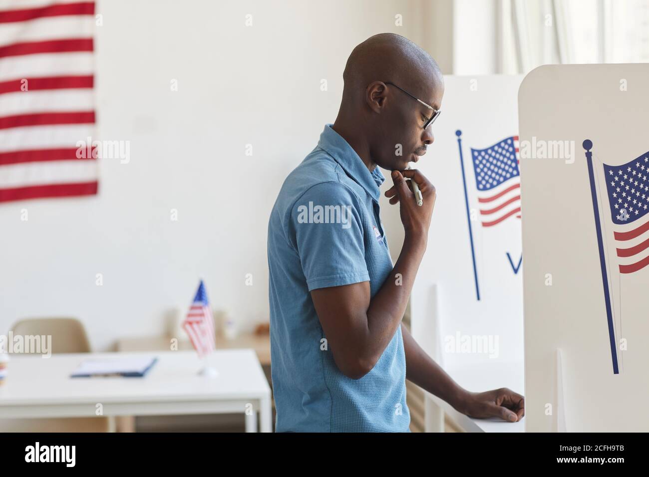 Vista laterale ritratto di giovane afroamericano in piedi in cabina di voto e pensare, copia spazio Foto Stock
