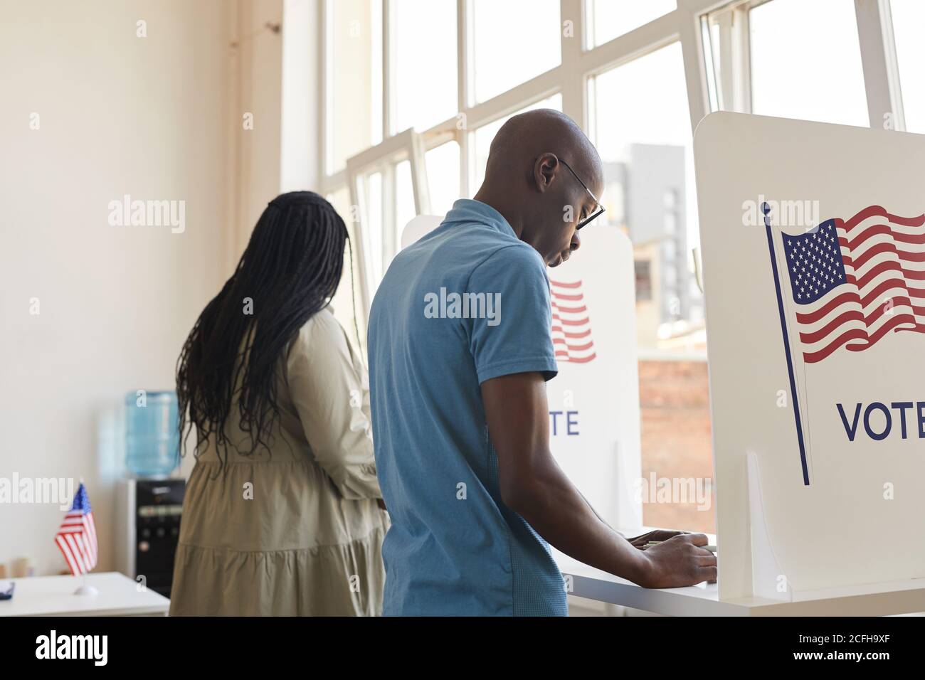 Indietro vista ritratto di giovani afroamericani in piedi in cabina di voto e pensare, copia spazio Foto Stock