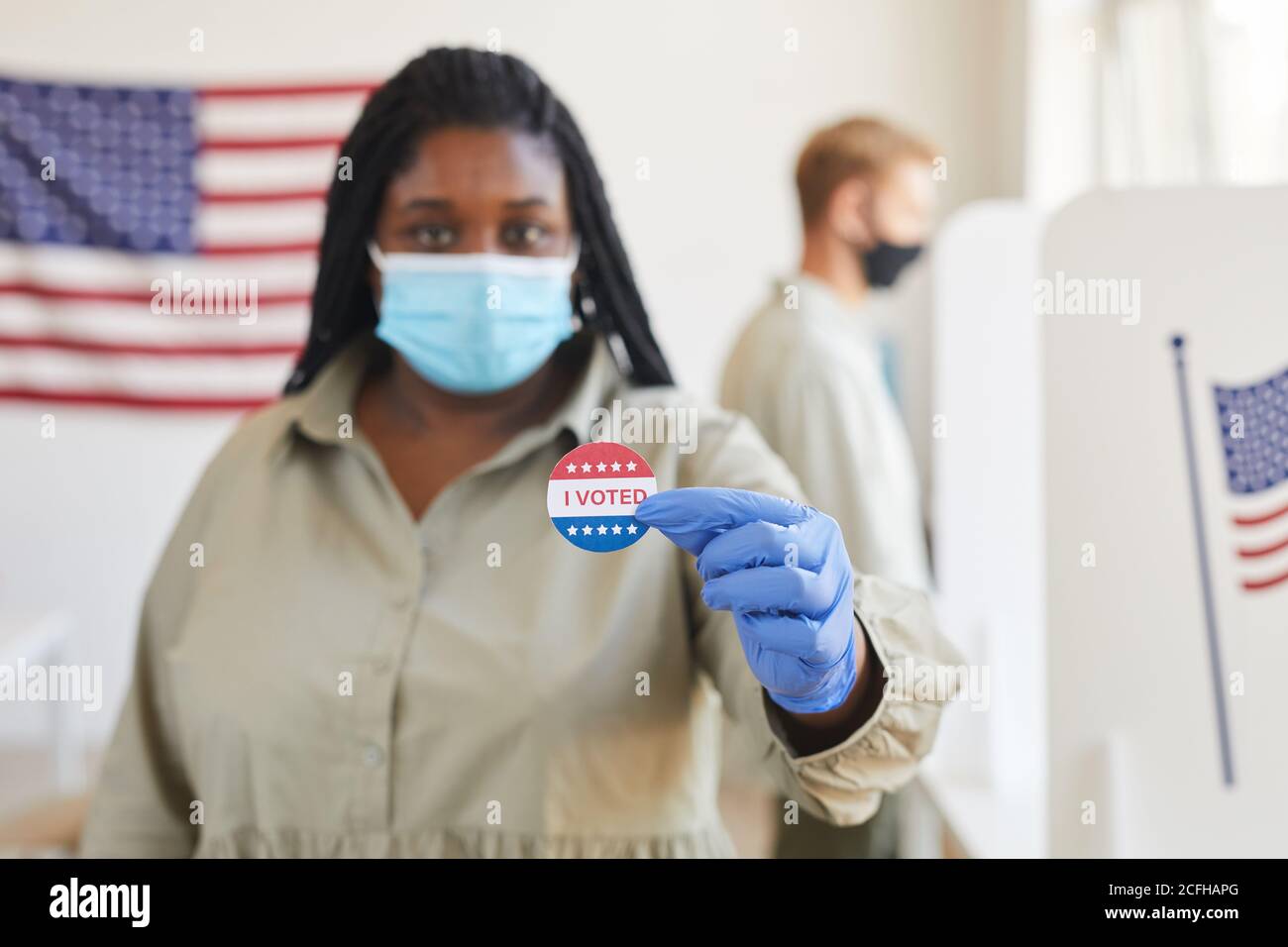 Ritratto offuscato della donna afroamericana che tiene ho VOTATO adesivo mentre in piedi t seggi il giorno delle elezioni post-pandemiche, copy space Foto Stock