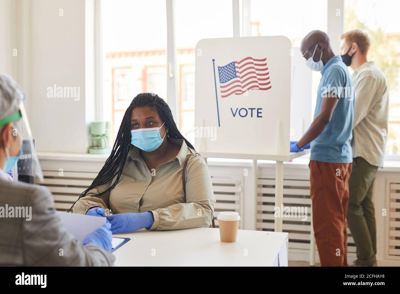 Gruppo multietnico di persone che indossano maschere di voto alla stazione di voto nel giorno delle elezioni post-pandemiche, copy space Foto Stock