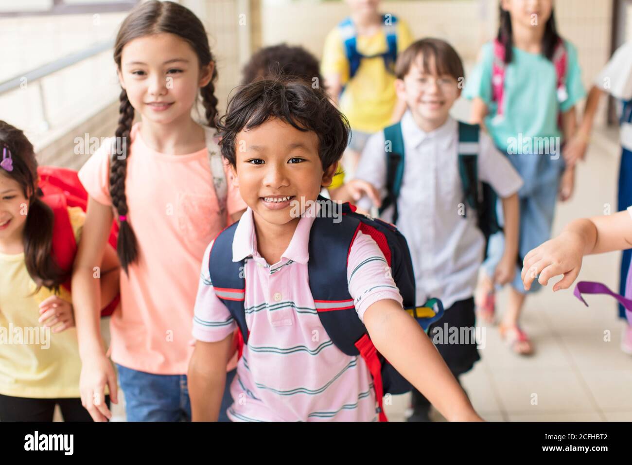 Gruppo felice di bambini della scuola elementare che corrono in avanti Foto Stock