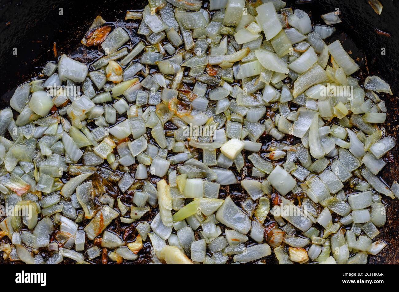 Cipolle saltate in padella. Friggere cipolle tritate finemente. Cibo semplice fatto in casa. Cucina. Vista dall'alto ad angolo. Messa a fuoco selettiva. Foto Stock